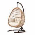 Sedia a dondolo sospesa in rattan sintetico con struttura in metallo e cuscini crema